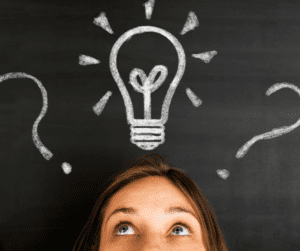 Na tle tablicy widać połowę twarzy dziewczynki. Nad jej głową kredą narysowane są dwa znaki zapytania (po prawej i lewej stronie), a na środku - żarówka